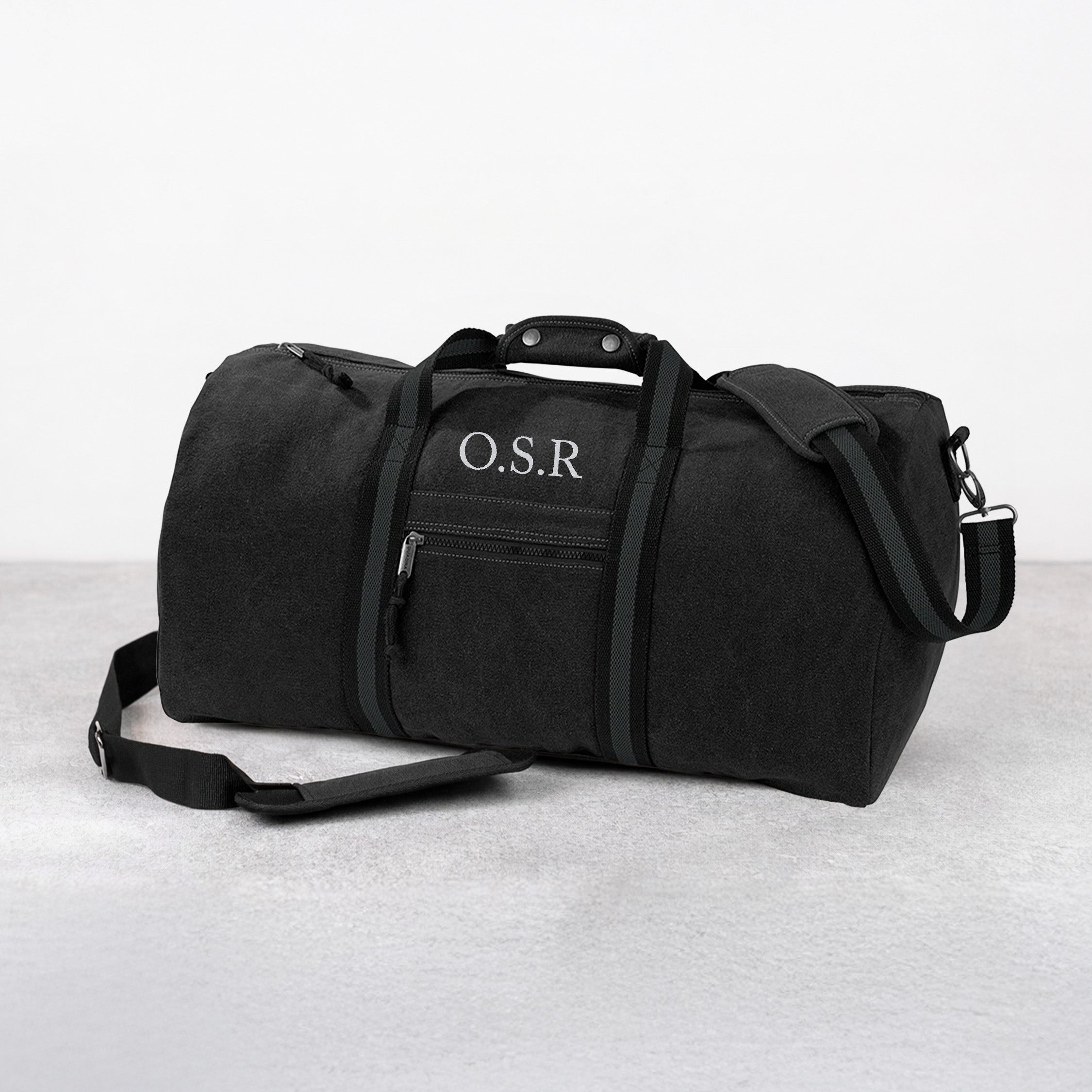 Black duffel bag with 'O.S.R' monogram on a light gray background