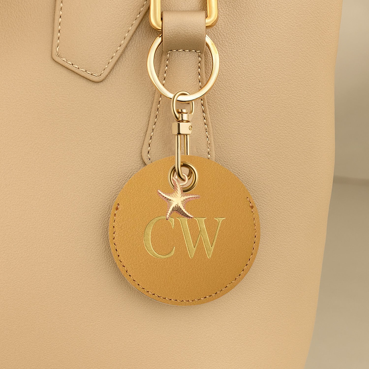 Leather keychain with initials 'CW' attached to a beige handbag.